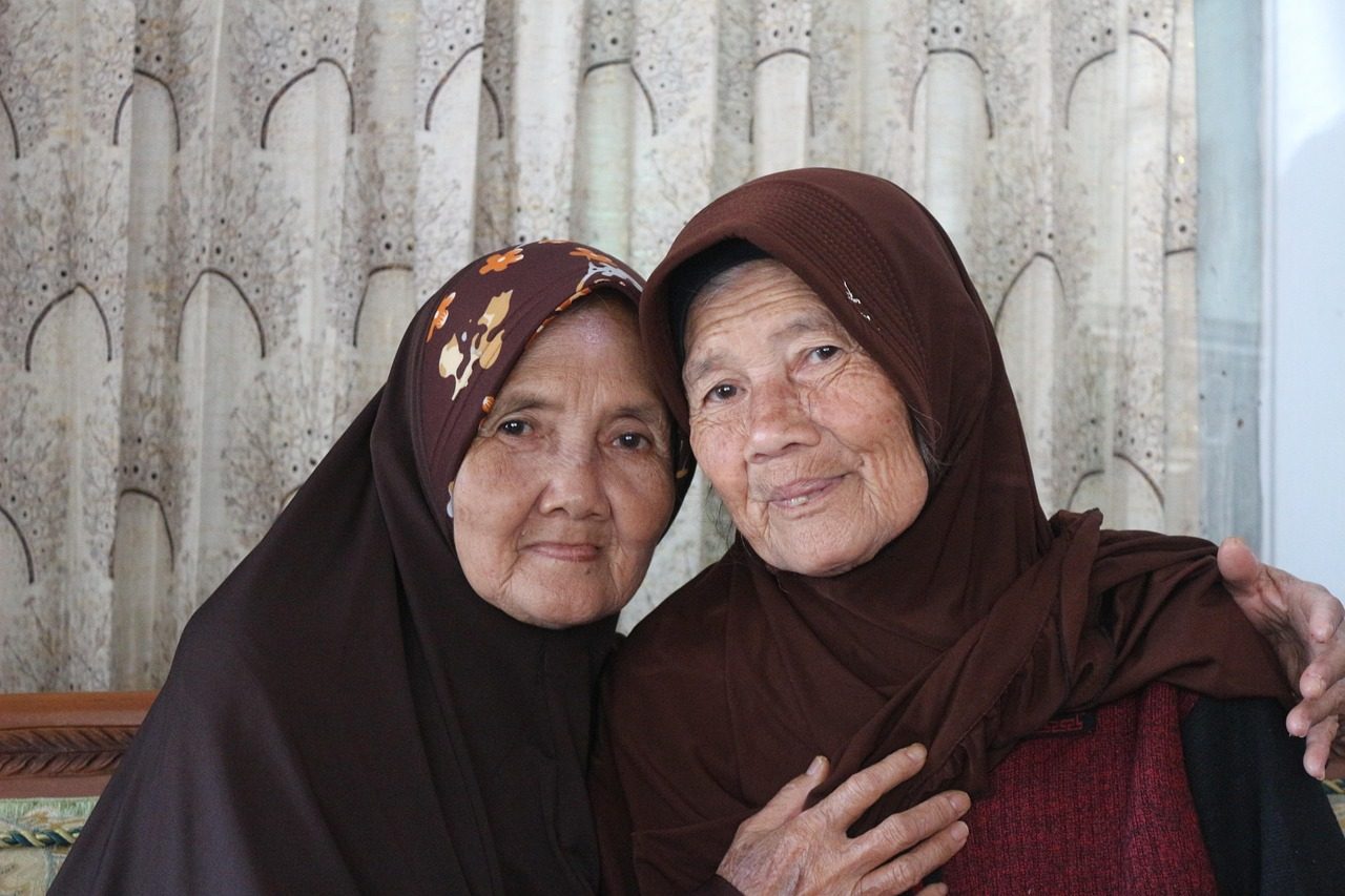 Stock photo of two senior friends smiling together. Models are not clients.